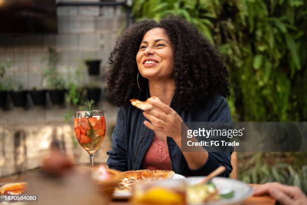 mid adult woman talking and eating with friends at restaurant - restuarant stock pictures, royalty-free photos & images
