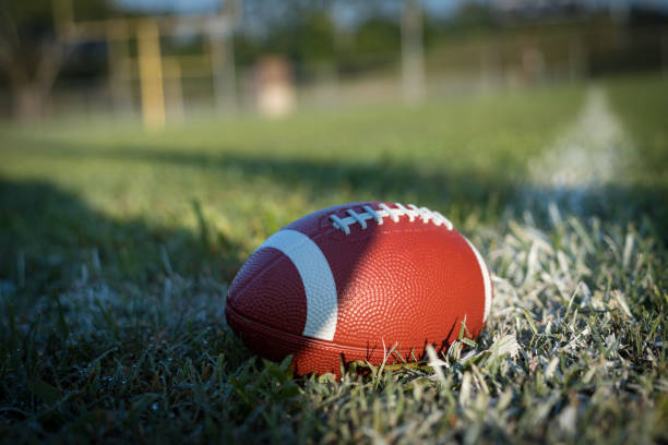football in grass on white line in field - american football stock pictures, royalty-free photos & images