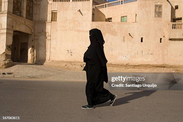 a woman dressed on a black niqab walking - tarim yemen stock pictures, royalty-free photos & images