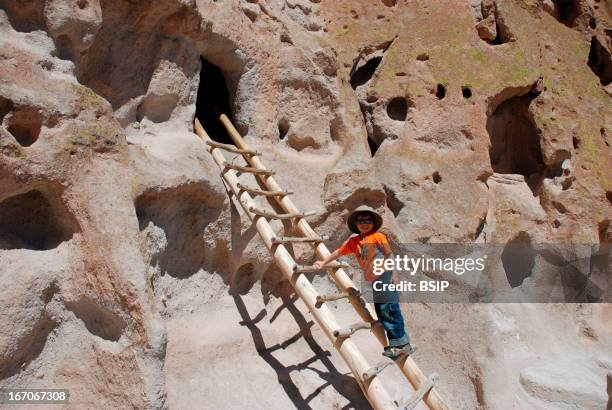 Children climbing into a troglodyte house of Bandelier National Monument. These cave dwellings were inhabited by the Pueblo Indians.