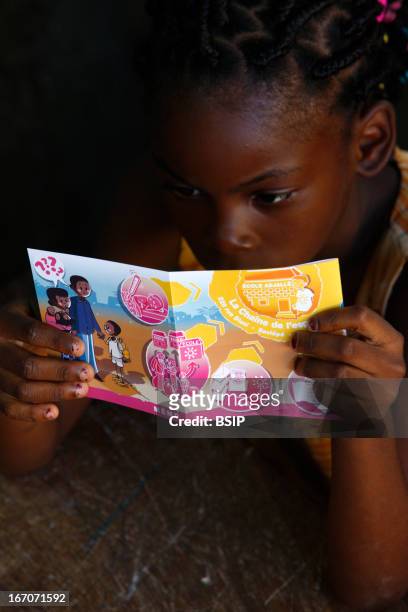 An African child, Photo essay in Lome in Togo, West Africa. Child reading an informative brochure of the association Chain of hope on children...