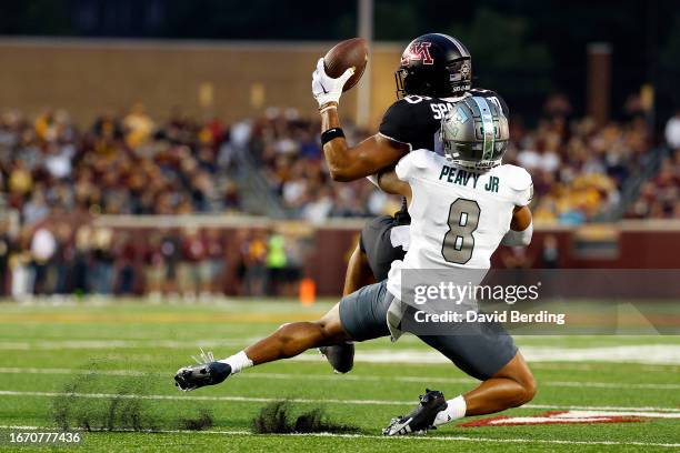 Brevyn Spann-Ford of the Minnesota Golden Gophers catches a pass as he's tackled by T.J. Peavy of the Eastern Michigan Eagles in the first half at...