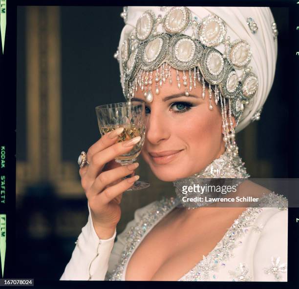American singer and actress Barbra Streisand holds a wine glass up to her eye during the filming of 'On a Clear Day You Can See Forever' , Brighton,...
