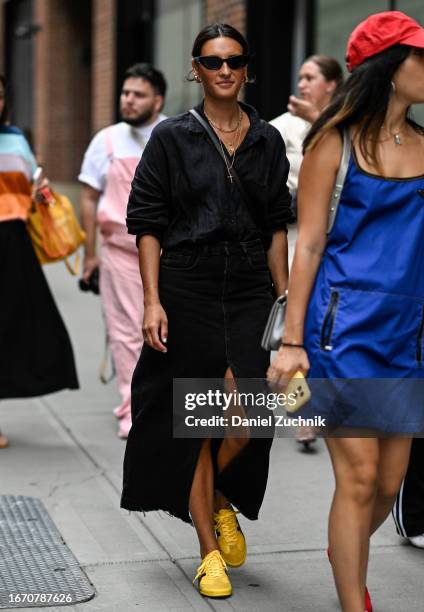 Guest is seen wearing a black top, black sunglasses, denim black skirt and yellow sneakers outside the Tibi show during NYFW S/S 2024 on September...