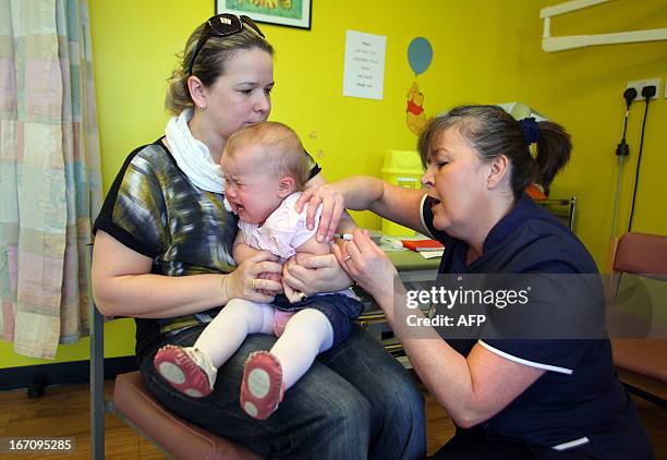 Month-old Amelia Down sits on the lap of her mother Helen as she receives the combined Measles Mumps and Rubella vaccination at an MMR drop-in clinic...