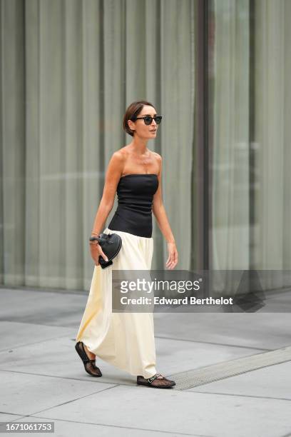 Geraldine Boublil wears a black off-shoulder top, a heart-shaped bag, a white maxi skirt, mesh shoes, outside Proenza Schouler, during New York...