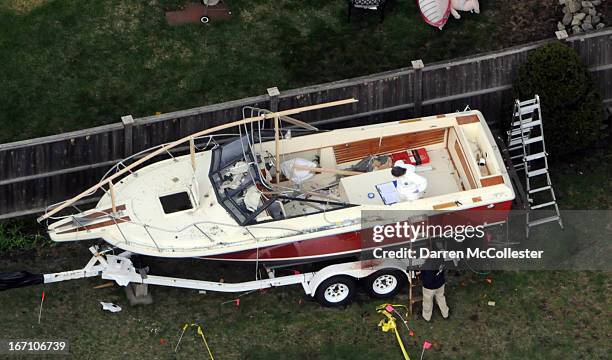 Investigators work around the boat where Dzhokhar A. Tsarnaev was found hiding after a massive manhunt, in the backyard of a Franklin Street home, in...