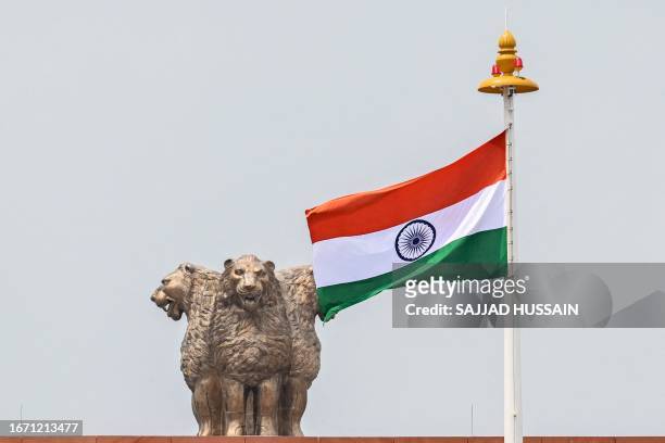 India's national flag flaps next to the 'National Emblem' at the newly constructed Indian parliament building after the flag hoisting ceremony in New...