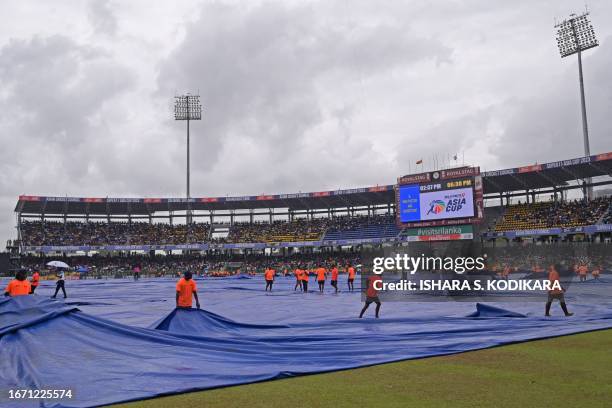 Ground staff cover the field as rain delays the start of the Asia Cup 2023 one-day international final cricket match between India and Sri Lanka at...