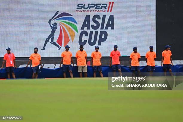 Ground staff cover the field as rain delays the start of the Asia Cup 2023 one-day international final cricket match between India and Sri Lanka at...