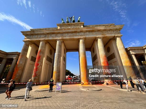 September 2023, Berln, Berlin: Members of the climate protection group Last Generation have sprayed the Brandenburg Gate in Berlin with orange paint....