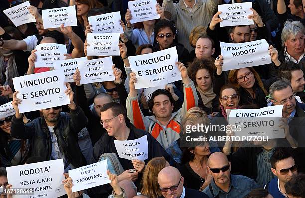 Supporters of Beppe Grillo's Five-Star Movement hold placards reading "The mess is served" to protest against Giorgio Napolitano's election as...