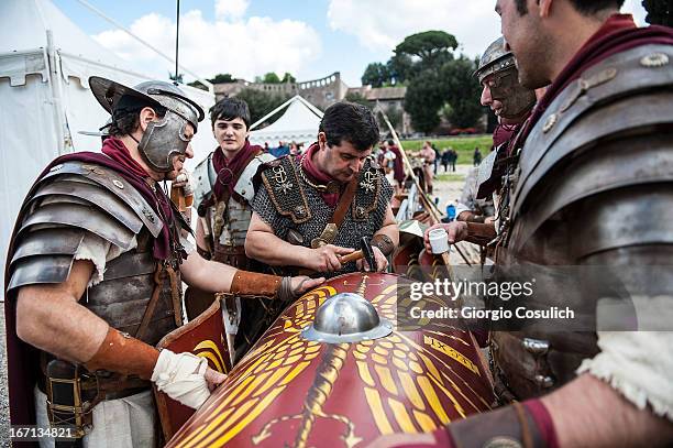 Actors dressed as ancient Roman soldiers repair a shield before to march in a commemorative parade during festivities marking the 2,766th anniversary...