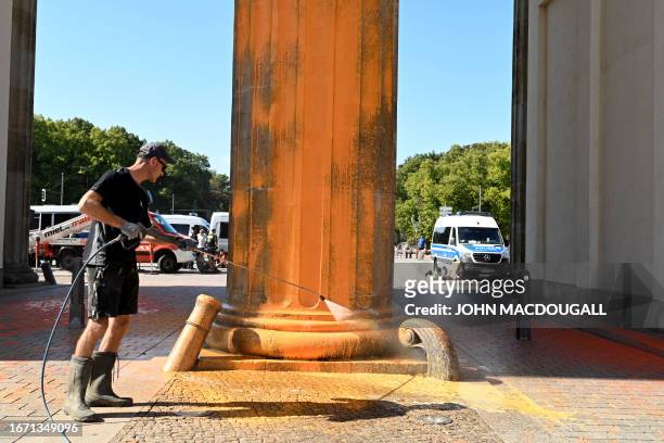 Man removes paint from one of the columns of Berlin's landmark the Brandenburg Gate on September 17, 2023 in Berlin. Activists of the "Last...