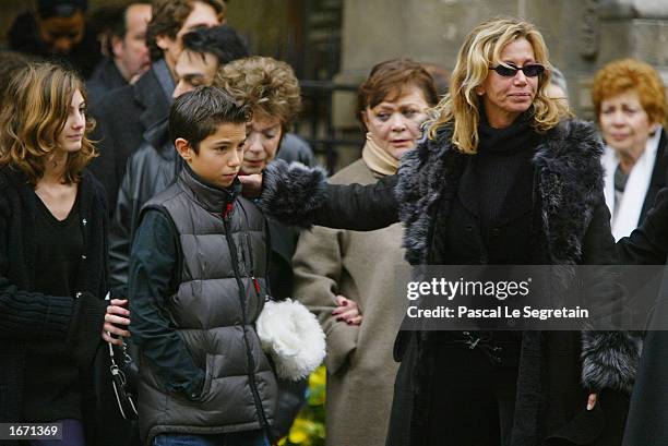 French actress Fiona Gelin holds her son as she leaves the Church of Saint Germain des Pres after the funeral for her father, French actor Daniel...