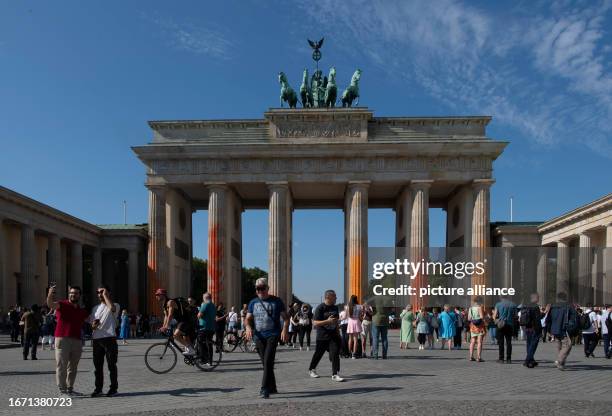 September 2023, Berln, Berlin: People are on the move at the Brandenburg Gate, which members of the climate protection group Last Generation sprayed...