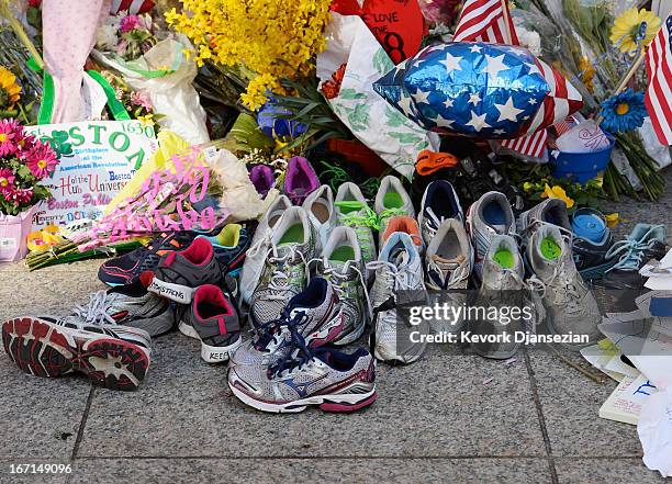 Running shoes are placed at a makeshift memorial for victims near the finish line of the Boston Marathon bombings at the intersection of Boylston...