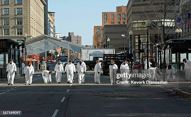 Law enforcement investigators walk near the finsh line of the Boston Marathon on Boylston Street looking for evidence after last Monday's bombings...