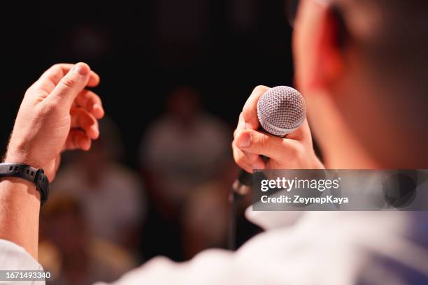 speeker parla al pubblico sul palco con il microfono - sponsor foto e immagini stock