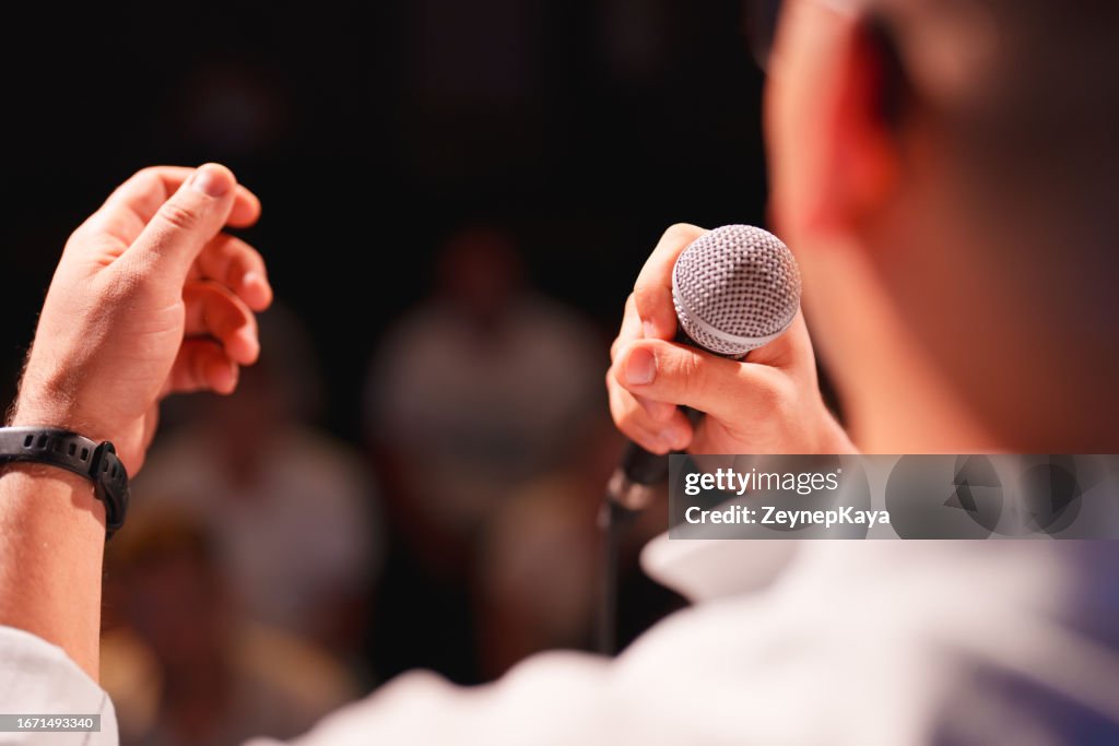 Speeker talking to audience on stage with microphone