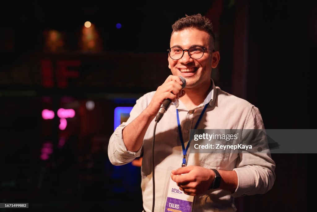 Speeker talking and showing a presentation to audience on stage with microphone