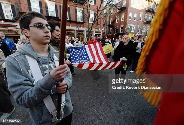 People hold an American flag during a candelight vigil for victims of Boston Marathon bombings on April 21, 2013 in Boston, Massachusetts. A manhunt...