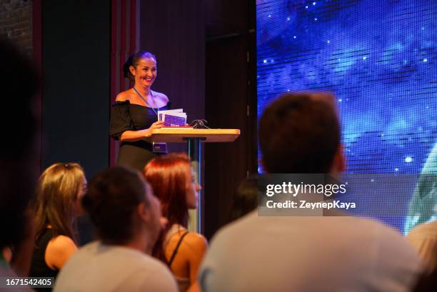 speeker talking and showing a presentation to audience on stage with microphone - female talk show host stock pictures, royalty-free photos & images