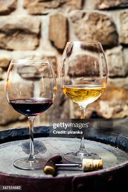 two glasses of red and white wine in the cellar - multi barrel stock pictures, royalty-free photos & images