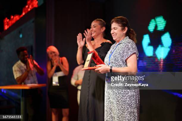 mid adult woman is receiving an award on stage for her speech - receiving award stock pictures, royalty-free photos & images