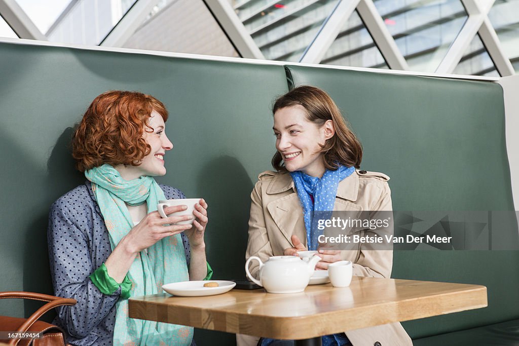 Female friends meeting up in cafe for chat.