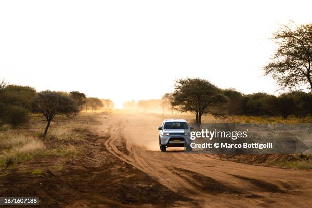 car driving on a gravel road at sunset in namibia, africa - south african culture stock pictures, royalty-free photos & images