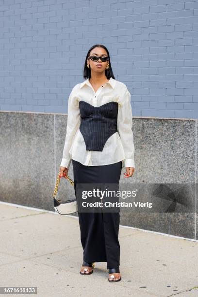 Guest wears black striped corset, white button shirt, skirt with slit outside Bevza on September 09, 2023 in New York City.