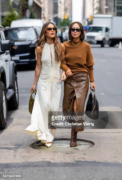 Camila Coelho wears creme white dress with slit, green bag, sunglasses & Aimee Song wears brown jumper, skirt with slit, boots outside Proenza...