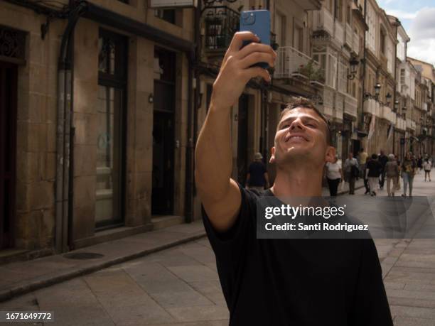 young man takes a selfie on the street to envy his friends - emoción stock pictures, royalty-free photos & images