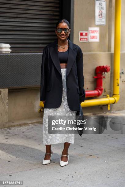 Guest wears wears black blazer, white transparent skirt, cropped top outside Tibi on September 09, 2023 in New York City.