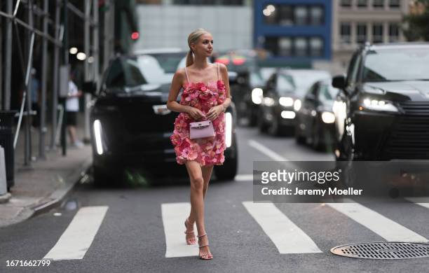 Leonie Hanne is seen wearing a mini dress with spaghetti straps and sewed on flowers in different shades of pink, several bracelets, golden rings, a...