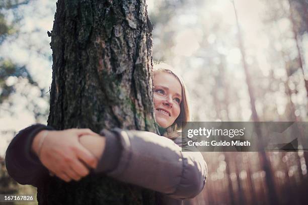 woman  hugging tree, smiling. - tree hugging stock pictures, royalty-free photos & images