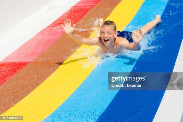 screaming child sliding down a water slide - summer fun in a water amusement park - acquapark foto e immagini stock