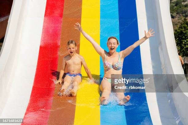 joyful mother and son having fun on a water slide on vacation - ウォータースライダー ストックフォトと画像