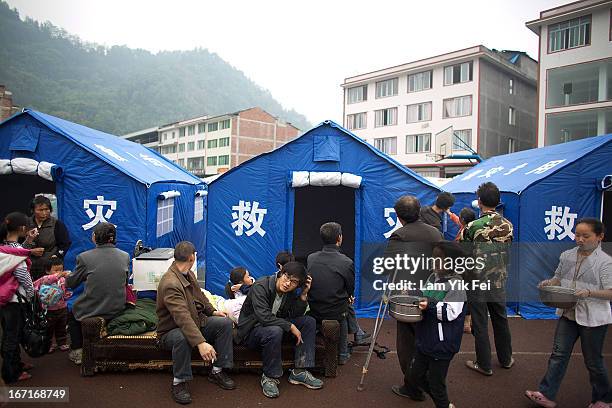People gather outside tents in a makeshift camp for earthquake survivors at BaoXing county, one of the hardest hit areas of the earthquake zone, on...