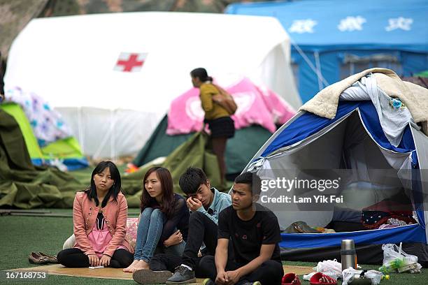 Survivors of a powerful earthquake sit outside tents at a makeshift camp in BaoXing county, one of the hardest hit areas of the earthquake zone, on...