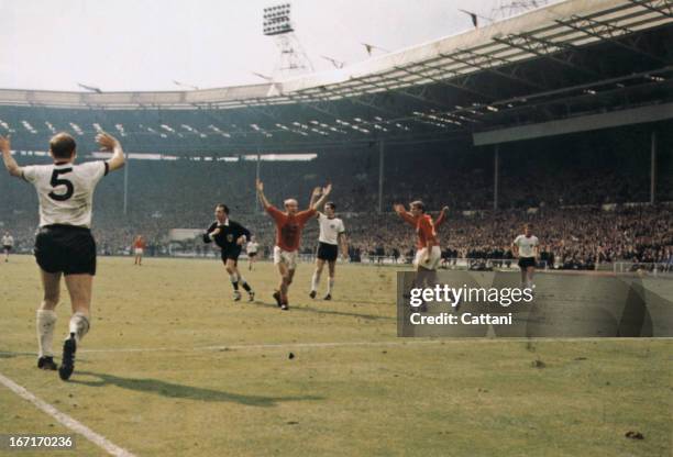 Bobby Charlton holds his hands up as West German players protest after Geoff Hurst scores the controversial third goal during the World Cup final at...