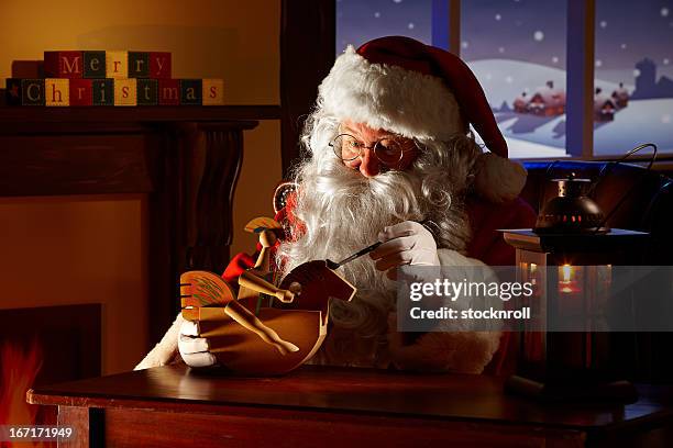 father christams painting a toy in his workshop - santas workshop stock pictures, royalty-free photos & images