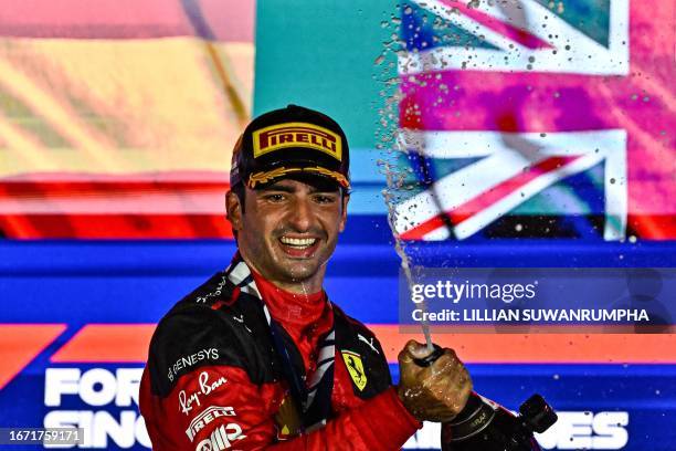 Ferrari's Spanish driver Carlos Sainz Jr sprays champagne as he celebrates on the podium after winning the Singapore Formula One Grand Prix night...