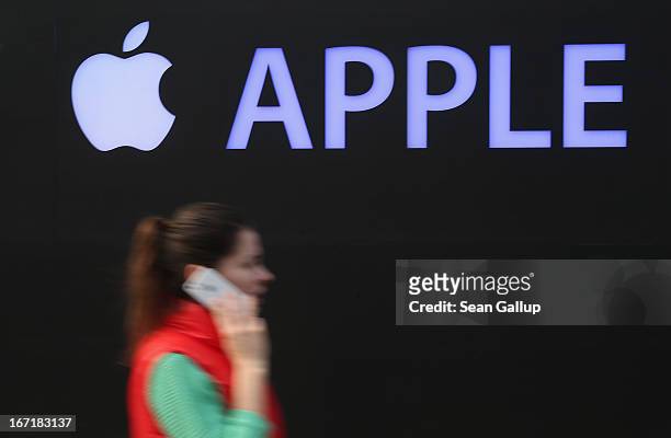 Young woman talks on an Apple iPhone as she walks past the construction site of the new Apple Store on Kurfuerstendamm avenue on April 22, 2013 in...