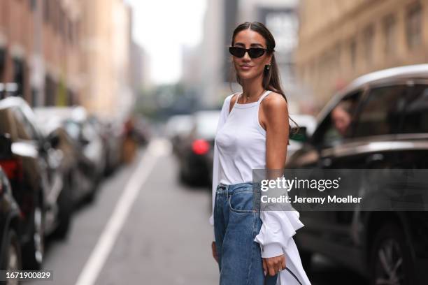 Tamara Kalinic is seen outside Tibi show wearing black sunnies, white tank top, white oversized shirt, high waisted pair of jeans, shiny silver...