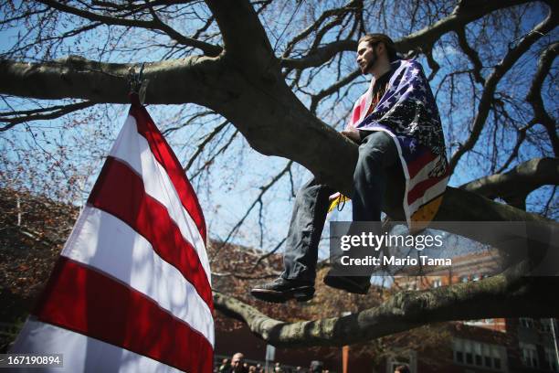 Devon Morancie sits on a tree branch while wearing an American flag outside the funeral for 29-year-old Krystle Campbell, who was one of three people...