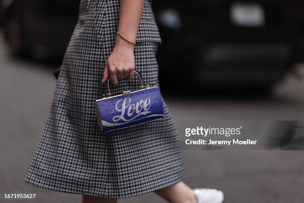 Guest is seen outside Tibi show wearing checkered skirt and a blue handbag with letters on it in white saying Love on September 09, 2023 in New York...