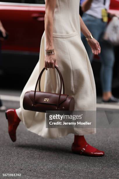 Guest is seen outside Tibi show wearing beige colored cotton dress with free arms, golden chunky bracelet, brown round shaped handbag woith golden...