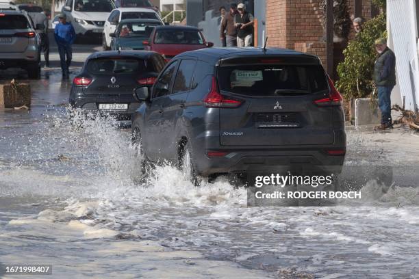 Cars drive through seawater from unusually large waves in the coastal village of Gordon's Bay, South Africa on September 17, 2023 following the...